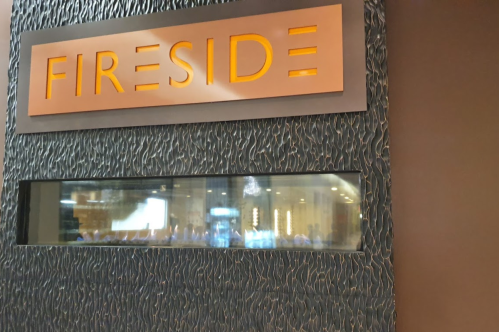 Sign reading "Fireside" above a textured wall with a window showing a blurred interior space.