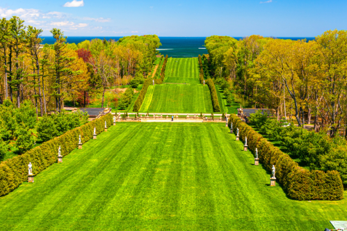 View of the green grass of rolling Castle Hill at the Ipswich Crane Estate. View is from the Great House, and the Ipswich Bay can be seen in the background.