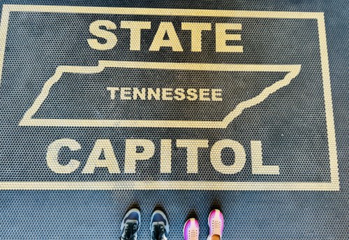 Feet standing on a mat with the words "STATE CAPITOL" and a map outline of Tennessee.