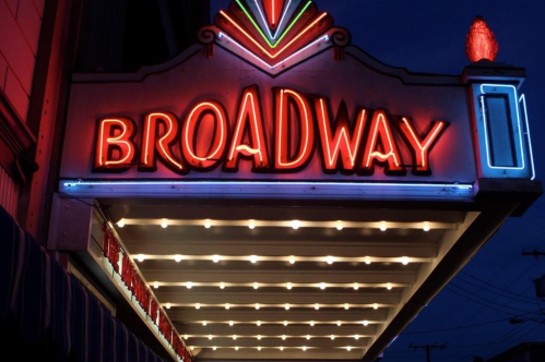 Neon sign reading "BROADWAY" illuminated at night, with colorful lights and a vintage marquee design.