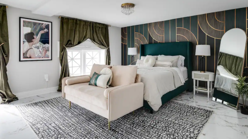 Modern bedroom featuring a green upholstered bed, elegant curtains, a cozy seating area, and stylish decor.