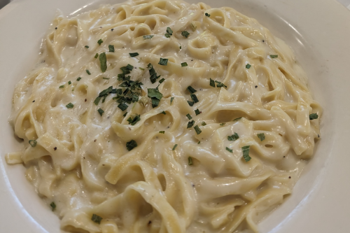 Well-seasoned alfredo noodles on a white dish.
