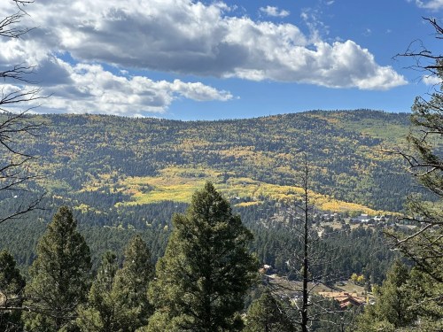 A scenic view of a mountainous landscape with vibrant autumn foliage and a small town nestled in the valley below.