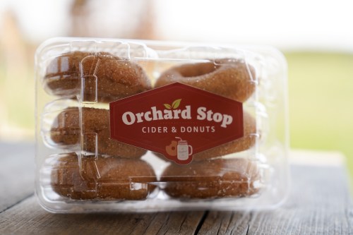 A clear plastic container holding several cinnamon sugar donuts from Orchard Stop Cider & Donuts.