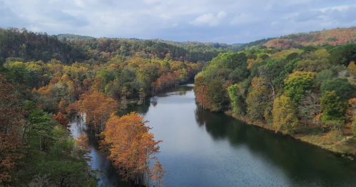 aerial view of the river running through the hills and forest in beavers bend state park during fall in oklahoma