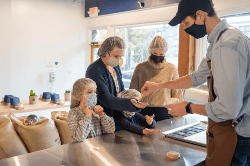 A family stands at a chocolate factory counter learning about how chocolate is made.