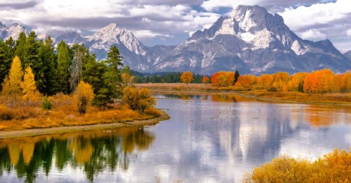 An aspen lake at Grand Teton National Park in Wyoming, surrounded by vibrant fall foliage.