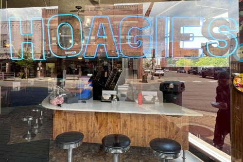 A diner window displays the word "HOAGIES" in neon, with a counter and stools visible inside.