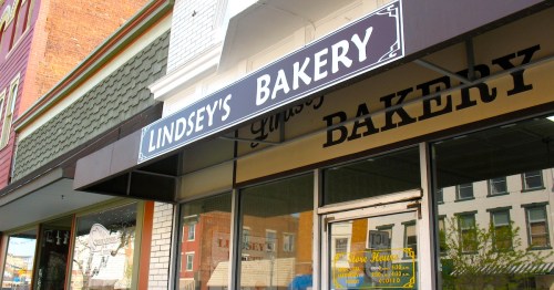 A brown awning over a storefront on a white brick building reads "Lindsey's Bakery."
