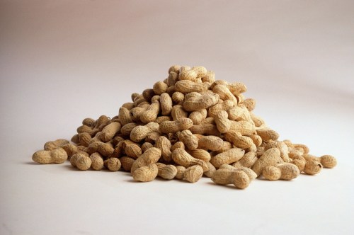A pile of unshelled peanuts on a light background.