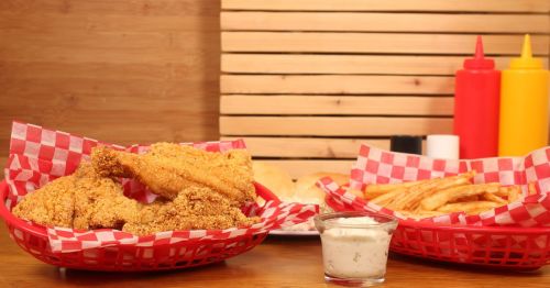 A heaping platter of golden fried catfish with French fries on the side at a diner.
