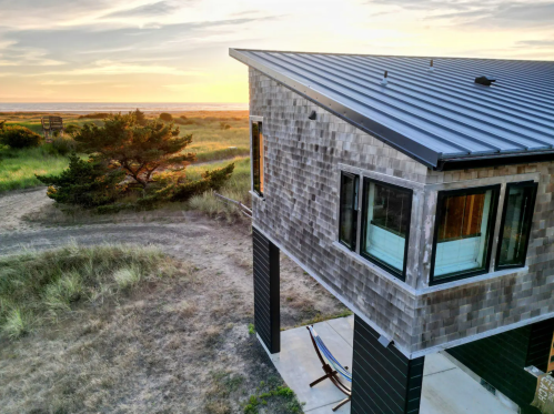 A beachfront cottage faces the Washington shoreline at sunset.