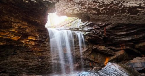 A waterfall tumbles through a cave ceiling opening at Raccoon Creek State Park.