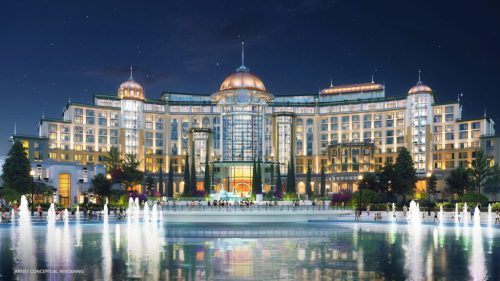 A grand hotel illuminated at night, featuring elegant architecture and a reflecting pool in front.