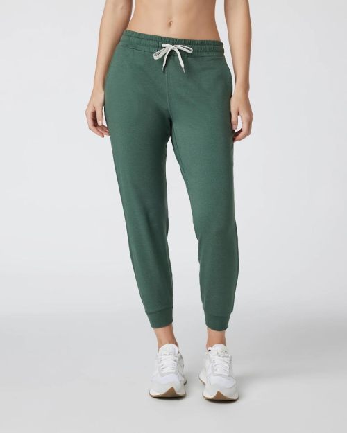 A person wearing green jogger pants and white sneakers, standing against a plain background.
