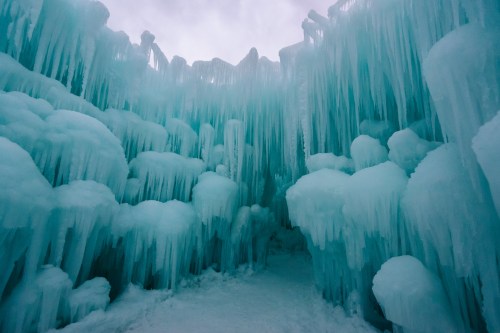 A stunning icy cavern with towering blue ice formations and icicles hanging from the walls, creating a serene winter scene.