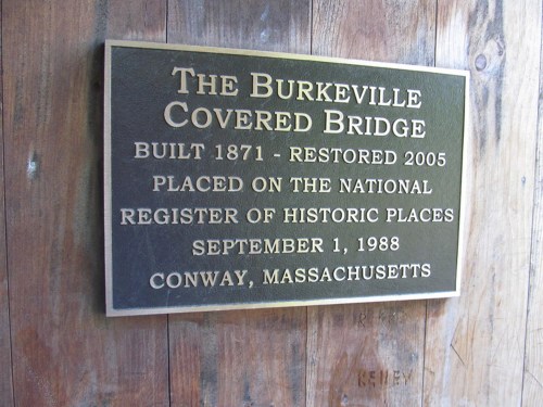 Plaque on the Burkeville Covered Bridge, detailing its history and restoration, located in Conway, Massachusetts.