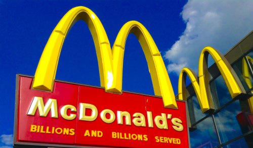 McDonald's sign featuring iconic golden arches against a blue sky, with the slogan "Billions and Billions Served."