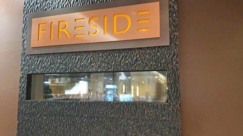 Sign reading "Fireside" above a textured wall with a window showcasing a blurred interior space.