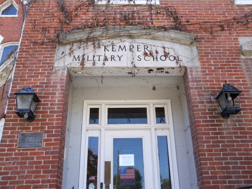 Entrance of Kemper Military School, featuring brick walls, ivy, and two lanterns beside the door.