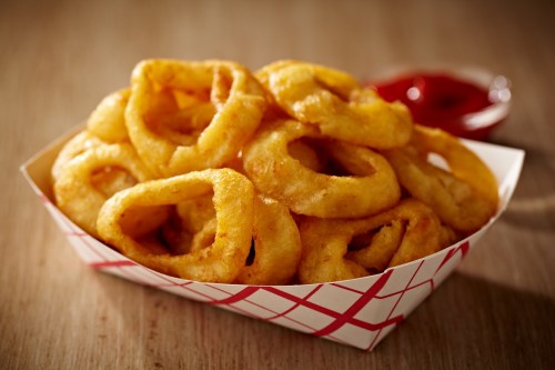 A basket of golden, crispy onion rings served with a side of ketchup.