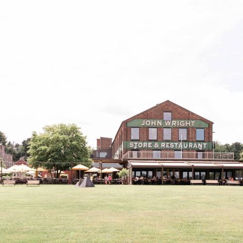 A brick building with "John Wright Store & Restaurant" sign, surrounded by green grass and outdoor seating.