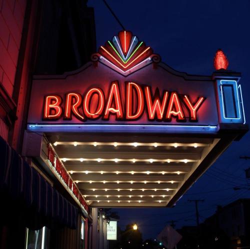 Neon Broadway theater marquee illuminated at night, featuring vibrant colors and a classic design.