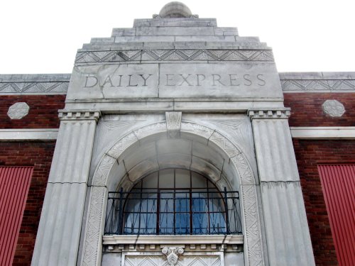 Facade of a historic building featuring the engraved words "DAILY EXPRESS" and decorative architectural details.
