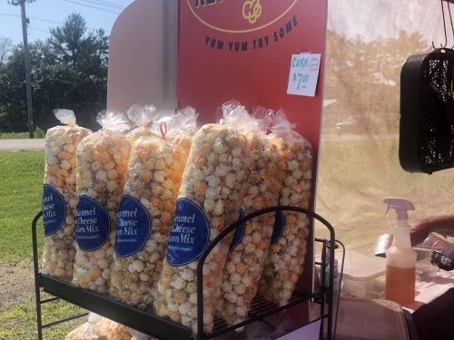 Bags of caramel and cheese popcorn displayed at a stand, with a sign advertising the price.