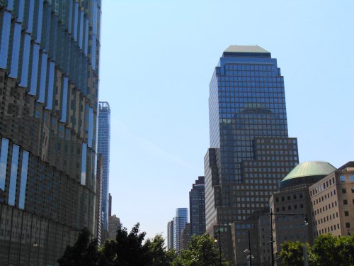 City skyline featuring modern skyscrapers and clear blue skies, with reflections on glass buildings.