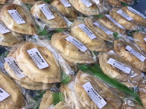 A variety of individually packaged fruit pies labeled "Peach Pie" and "Cherry Pie" arranged neatly.
