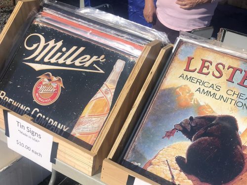 Two wooden boxes display vintage tin signs for Miller Brewing Company and Lester's Ammunition, priced at $10 each.