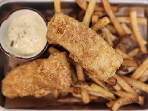 A plate of golden fried fish fillets served with crispy fries and a small bowl of dipping sauce.