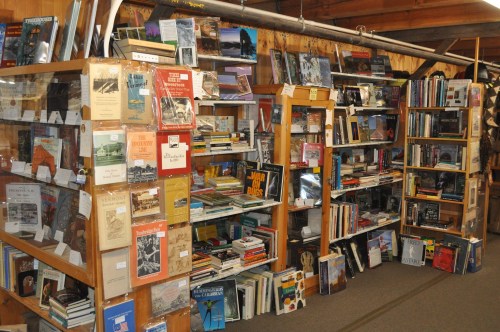 A cozy bookstore with wooden shelves filled with various books and magazines, showcasing a diverse collection.
