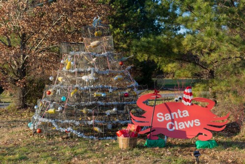 A festive crab trap Christmas tree with ornaments and a sign reading "Santa Claws" beside it.