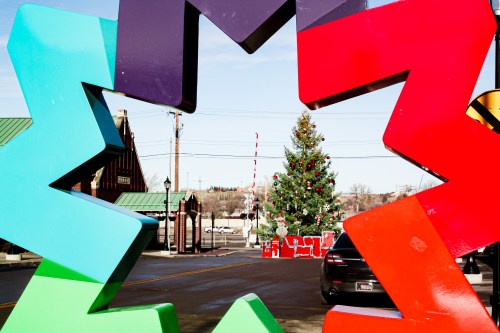 Colorful star-shaped frame with a view of a decorated Christmas tree and festive decorations in the background.
