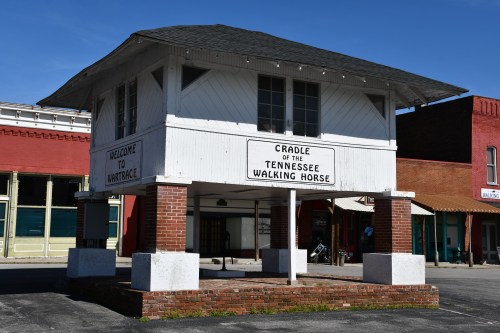 Historic building with a sign reading "Cradle of the Tennessee Walking Horse" in a small town setting.