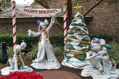 Holiday decorations featuring Disney characters Goofy, Pluto, and Mickey by a festive tree with a "Happy Holidays" sign.