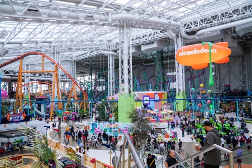 A vibrant indoor amusement park with rides, attractions, and colorful decor, bustling with visitors.
