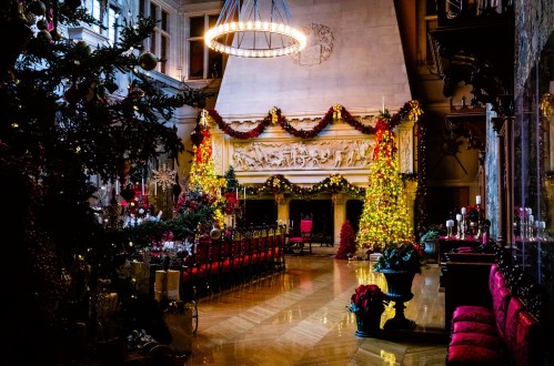 A beautifully decorated room for Christmas, featuring a grand fireplace, festive garlands, and a large dining table.