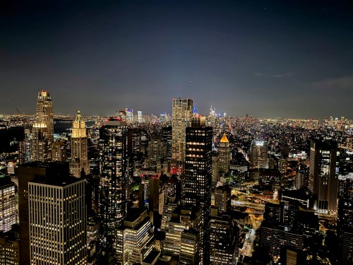 A panoramic view of a city skyline at night, illuminated buildings, and distant lights stretching across the horizon.