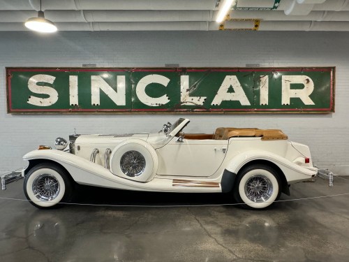 A vintage white convertible car displayed in front of a large green and white Sinclair sign.