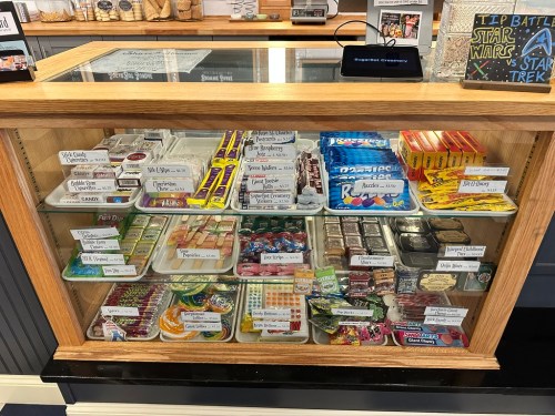 A display case filled with various candies and snacks, labeled for a Star Wars vs. Star Trek tip battle.