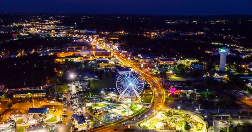 A night aerial view of Hwy. 76 and the many tourist attractions in Branson, Missouri. Many colorful amusement park attraction lights, cars on the street can be seen.