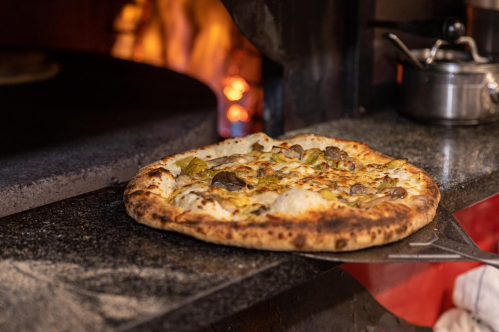 A mushroom pizza being pulled from a wood-oven at the Wandby Landing restaurant in Kennebunk, Maine.