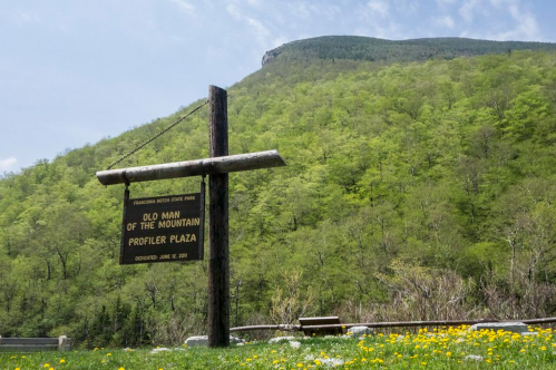 View of mountain at the Old Man of the Mountain Profiler Plaza at NH's Franconia Notch State Park. A sign in front of the mountain reads " Old Man Of The Mountain Profiler Plaza."