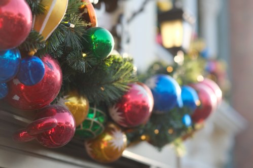 Colorful Christmas ornaments and greenery decorate a festive garland, creating a cheerful holiday atmosphere.