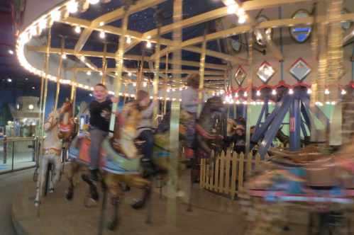 Children joyfully riding a carousel, surrounded by colorful lights and whimsical decorations.