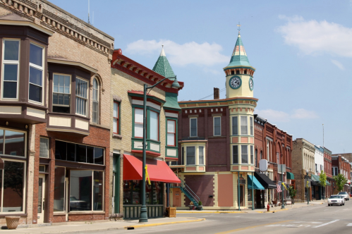 Colorful historic buildings line a street, featuring a distinctive clock tower and vibrant storefronts under a clear blue sky.