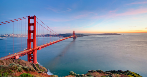 The Golden Gate Bridge stretches over the water at sunset.